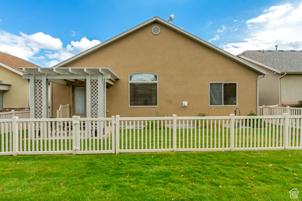 Back of house with stucco siding and a pergola