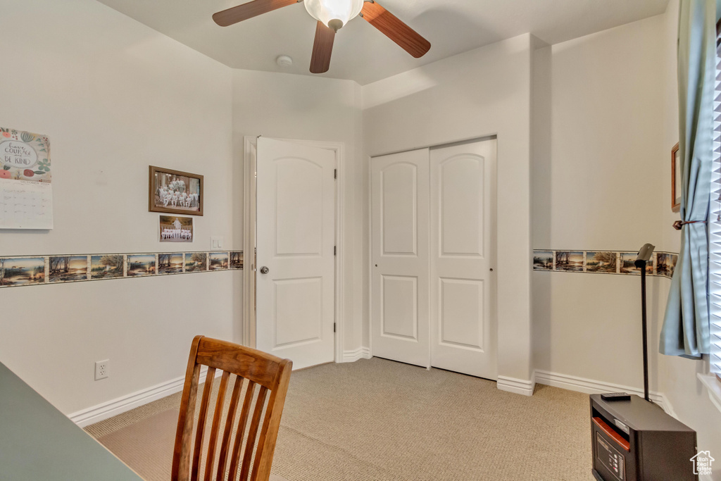Carpeted home office featuring ceiling fan and baseboards