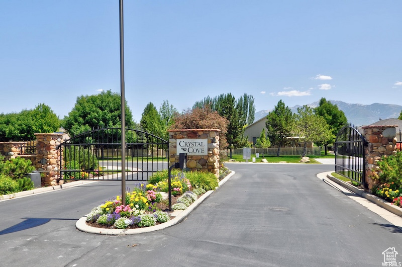 View of asphalt road featuring a gate, a gated entry, curbs, and a mountain view