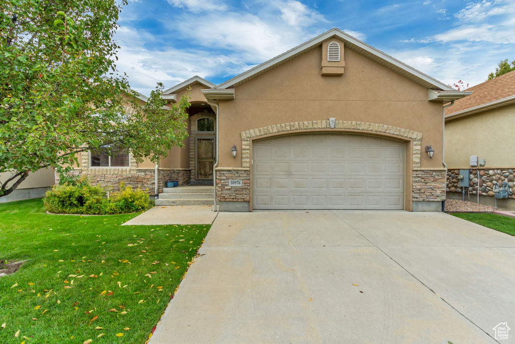 View of front of house with stone siding, stucco siding, and driveway