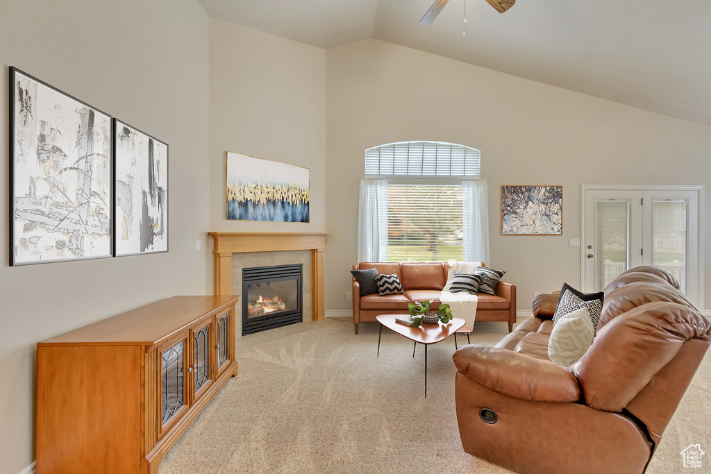 Carpeted living area with high vaulted ceiling, a fireplace, and ceiling fan