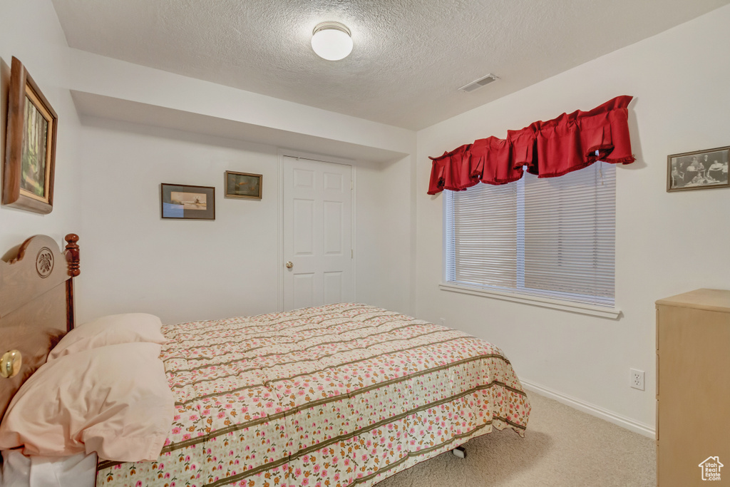 Carpeted bedroom with a textured ceiling and baseboards
