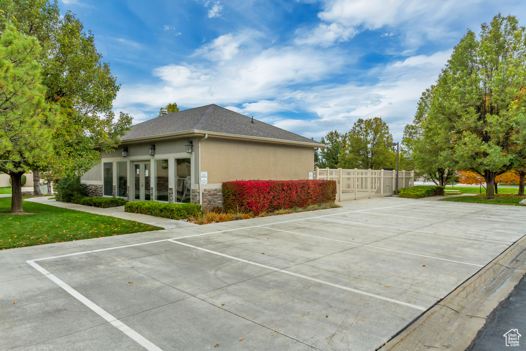 View of property exterior featuring stucco siding, stone siding, french doors, and uncovered parking