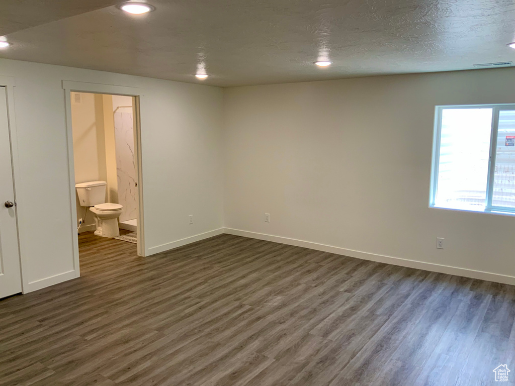 Unfurnished bedroom with dark wood-style floors, ensuite bath, and recessed lighting