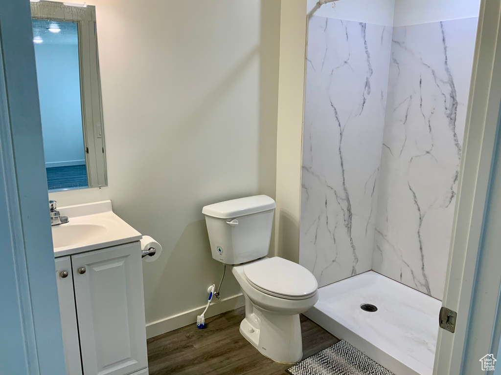 Full bath with a marble finish shower, vanity, and wood finished floors