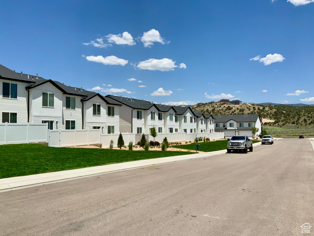 View of asphalt road featuring a residential view, sidewalks, and curbs