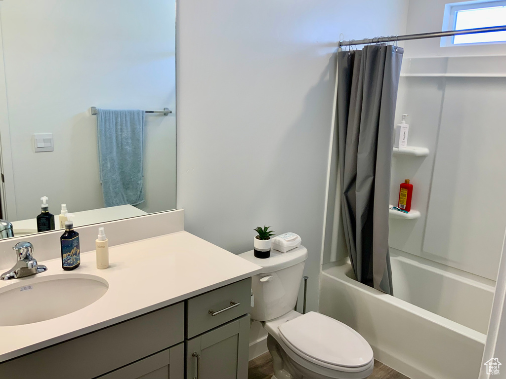 Bathroom with vanity, shower / tub combo, and wood finished floors