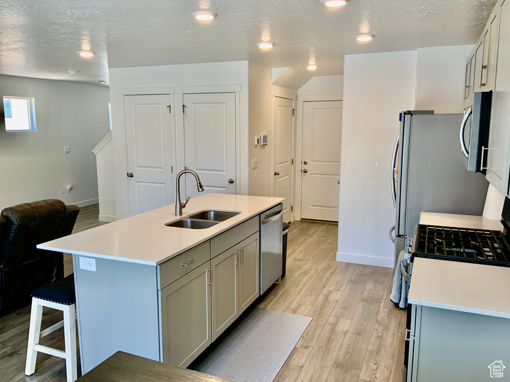 Kitchen with appliances with stainless steel finishes, light wood-style flooring, light countertops, gray cabinets, and recessed lighting