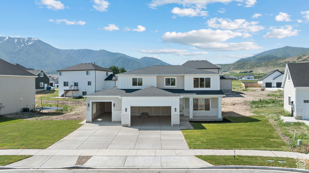 View of front of house with a mountain view, a garage, driveway, and a front yard