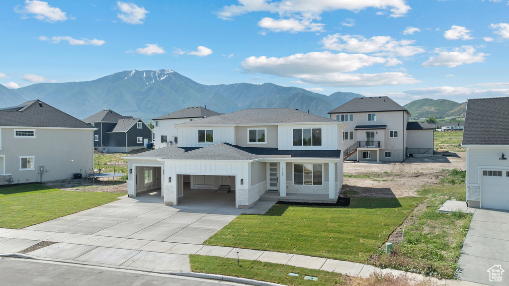 View of front of home featuring driveway, a mountain view, a shingled roof, a front yard, and a residential view