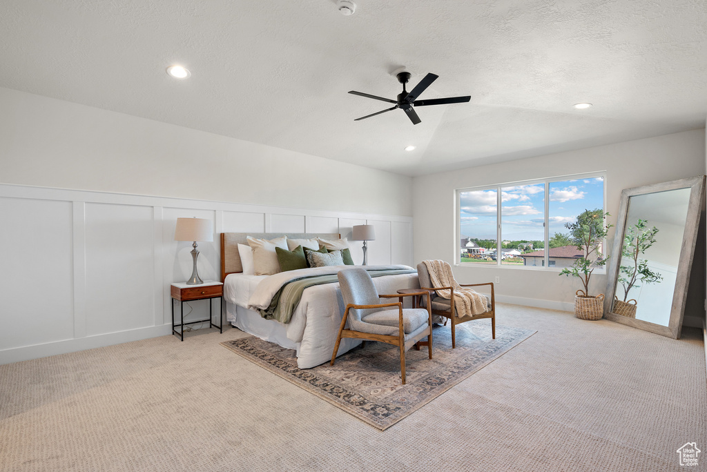 Carpeted bedroom featuring a decorative wall, recessed lighting, a ceiling fan, and wainscoting