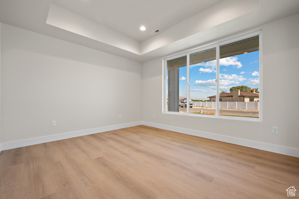 Unfurnished room with light wood-style floors, a raised ceiling, and recessed lighting