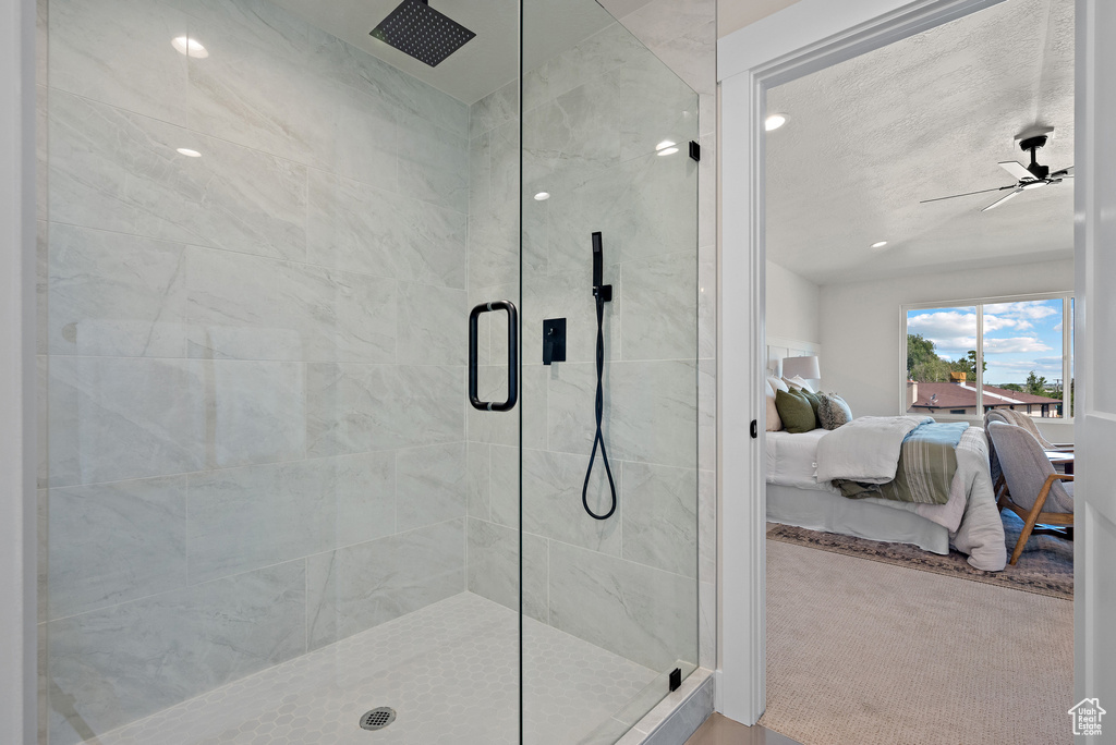 Ensuite bathroom featuring a stall shower, a ceiling fan, and lofted ceiling