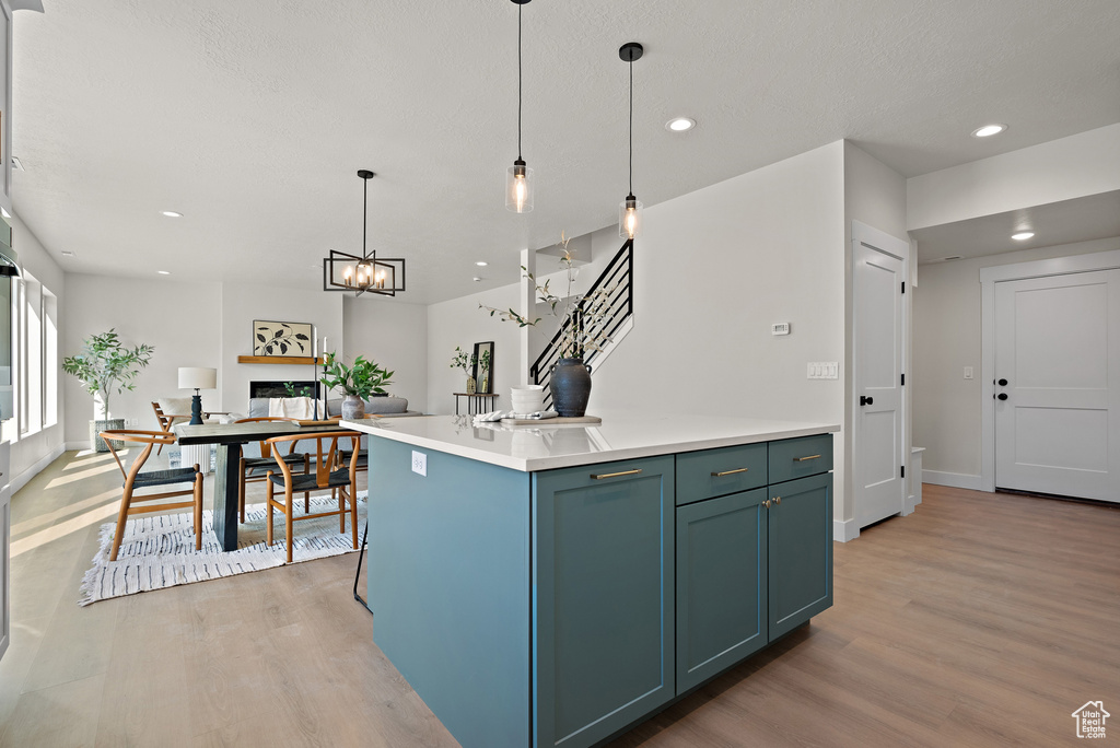 Kitchen featuring light wood finished floors, recessed lighting, decorative light fixtures, light countertops, and a center island