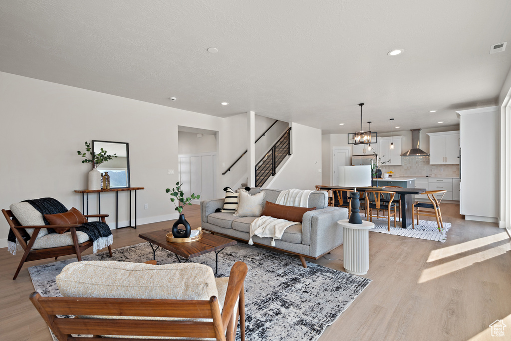 Living area featuring light wood-style flooring, recessed lighting, stairway, and a chandelier