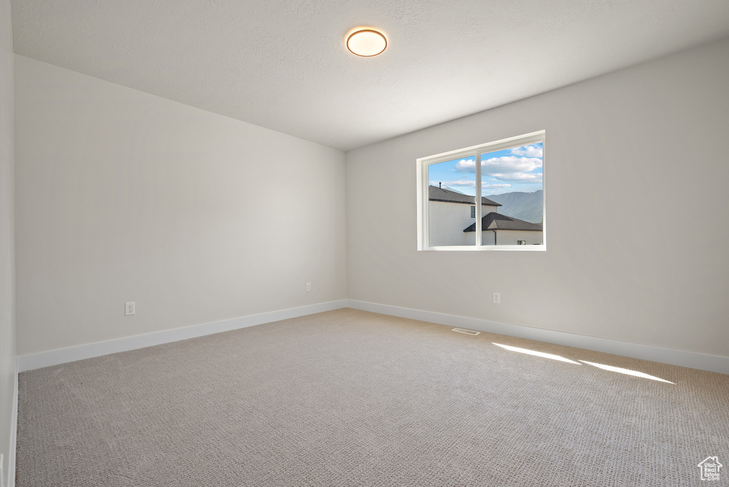 Empty room featuring light carpet and baseboards