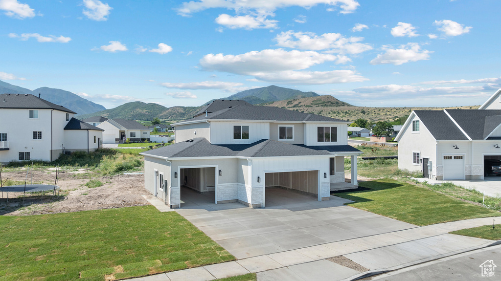 View of front facade featuring a mountain view, a residential view, a shingled roof, a front lawn, and concrete driveway