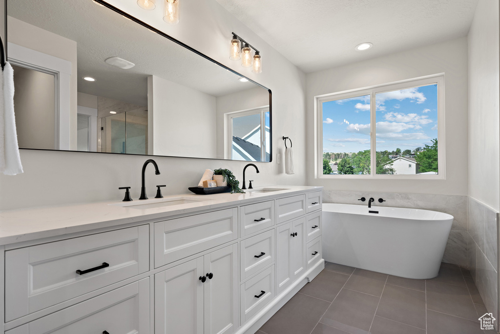 Full bath featuring double vanity, a freestanding tub, tile patterned flooring, recessed lighting, and a shower with shower door