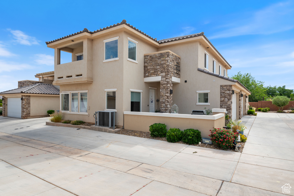 View of front of property with stone siding, stucco siding, driveway, a garage, and a tiled roof