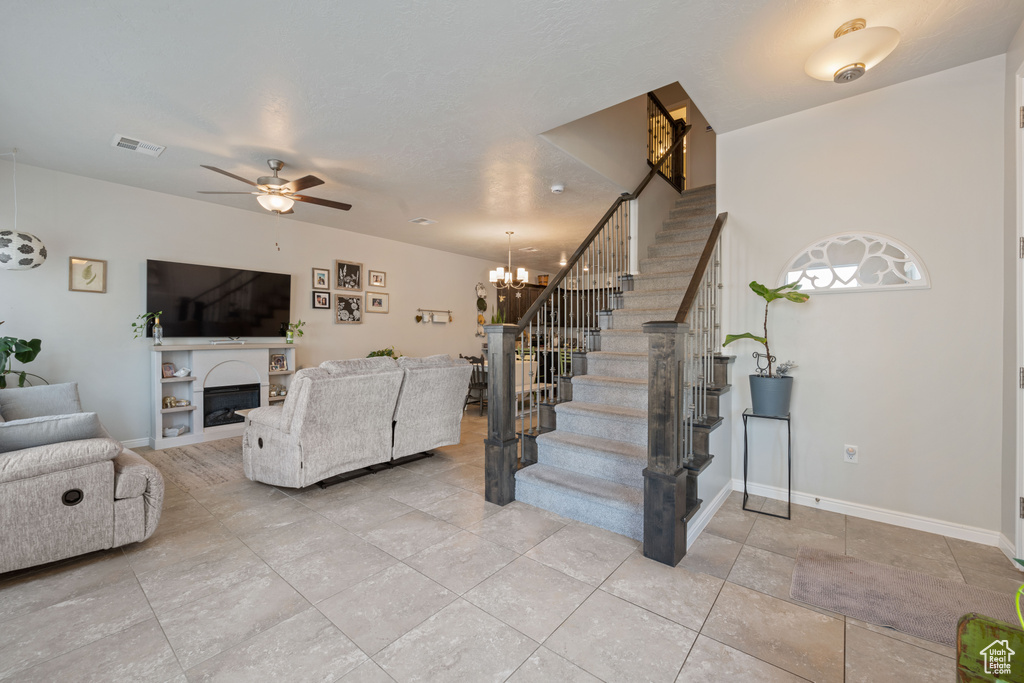 Living area with stairway, light tile patterned flooring, a fireplace, and a chandelier