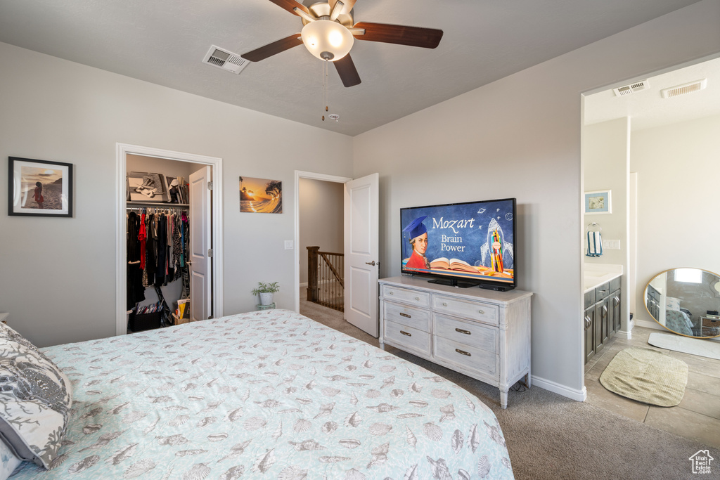 Carpeted bedroom with ceiling fan, a walk in closet, and connected bathroom