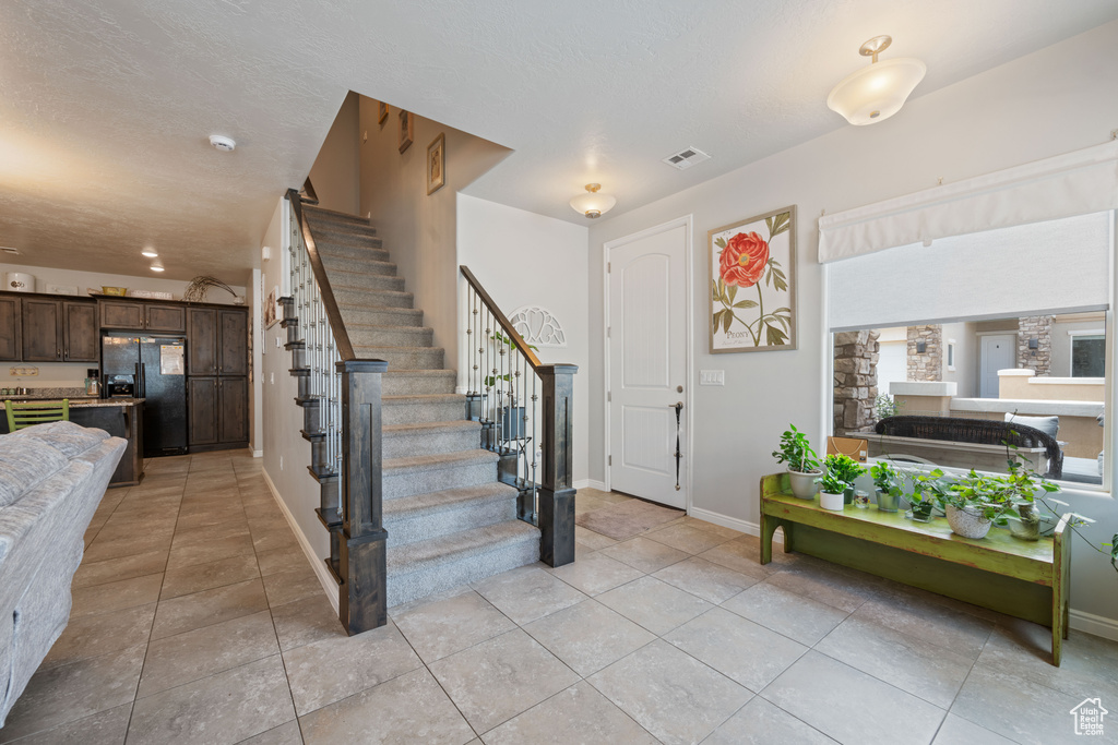 Entryway featuring stairway and light tile patterned flooring
