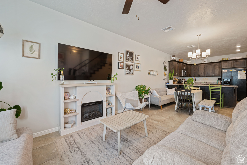 Living area featuring a ceiling fan, a chandelier, and stairway