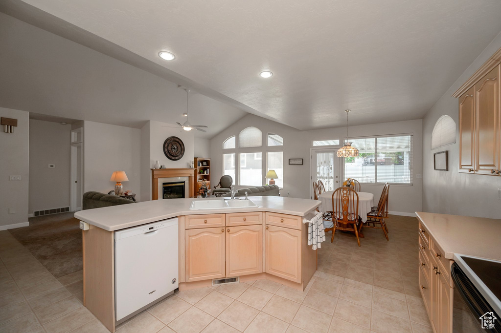 Kitchen with white dishwasher, open floor plan, a glass covered fireplace, light countertops, and lofted ceiling