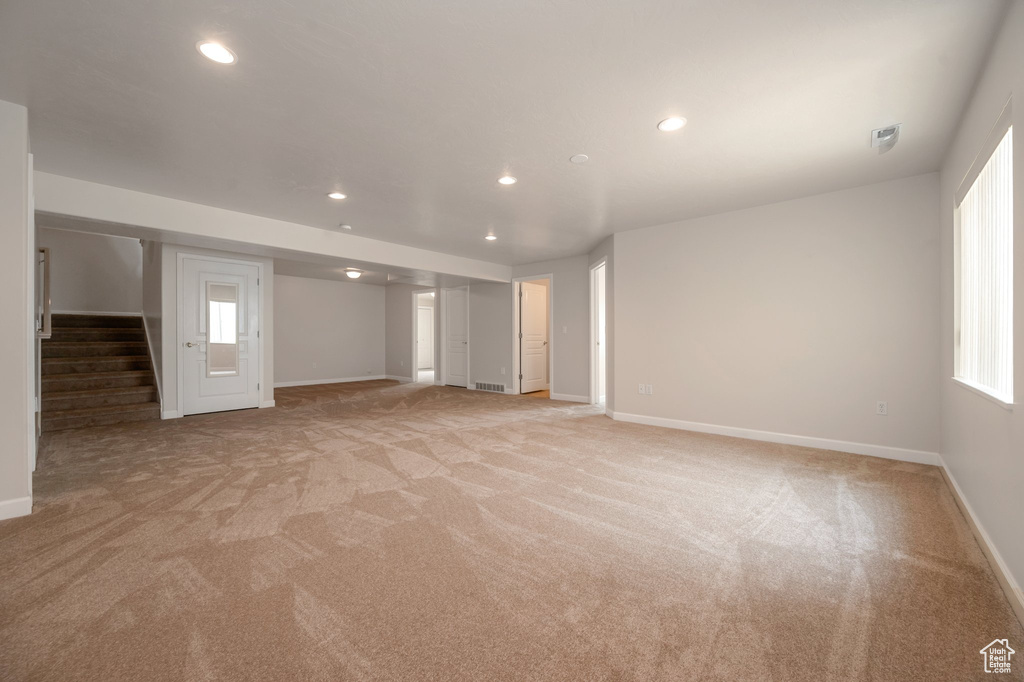 Basement featuring light colored carpet, stairway, recessed lighting, and plenty of natural light