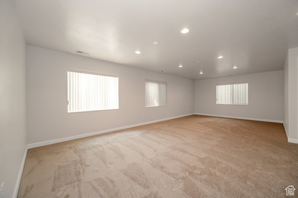Empty room with light colored carpet and recessed lighting