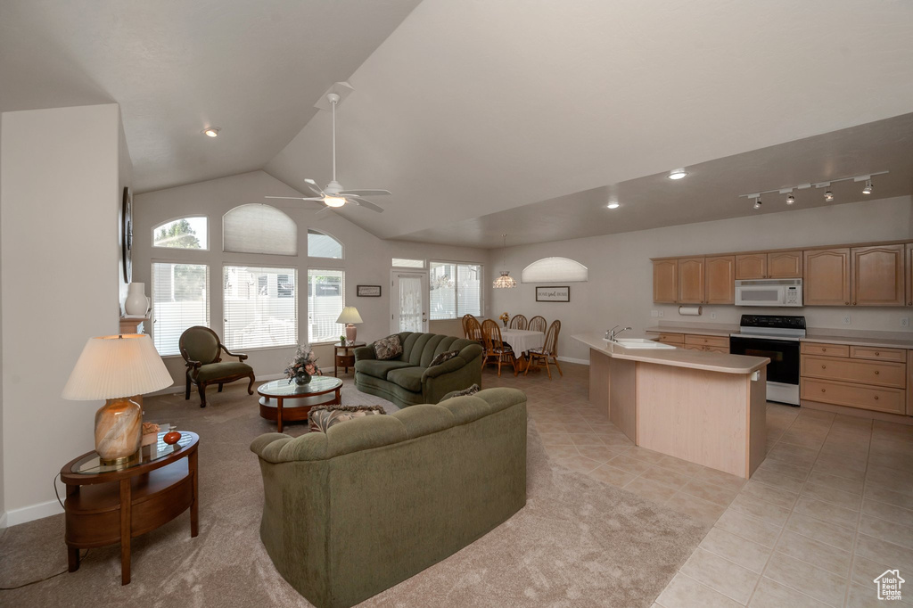 Living room with a ceiling fan, plenty of natural light, light tile patterned floors, and high vaulted ceiling