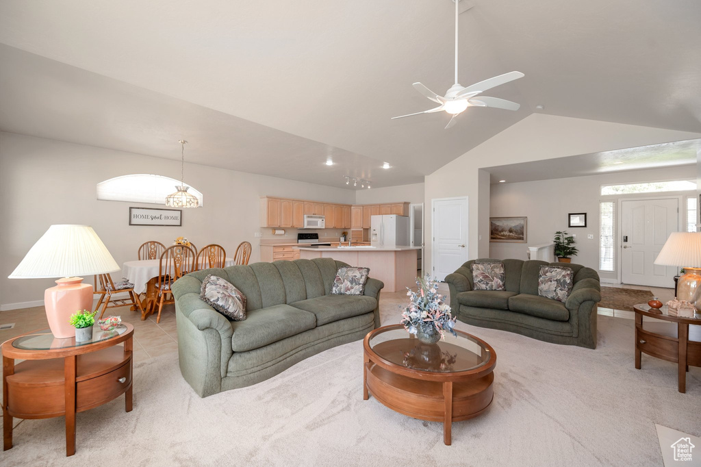 Living area with lofted ceiling, a ceiling fan, and light carpet