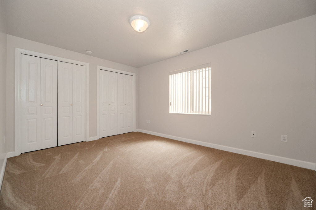 Unfurnished bedroom featuring two closets and carpet