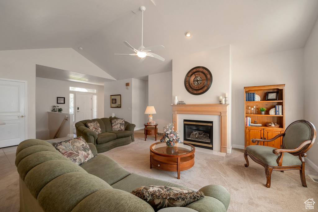 Living room featuring vaulted ceiling, a fireplace, light colored carpet, and a ceiling fan