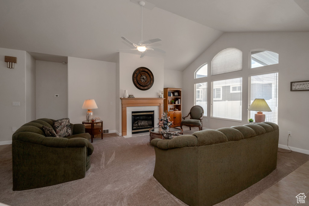 Carpeted living area featuring a ceiling fan, a fireplace with flush hearth, and high vaulted ceiling