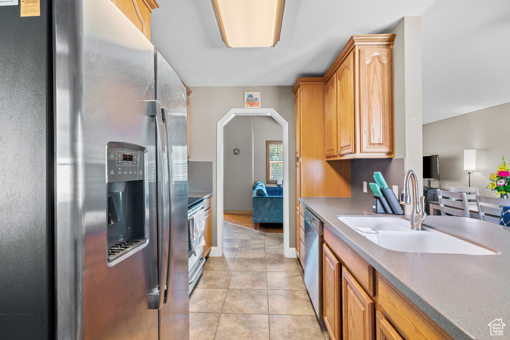 Kitchen with stainless steel appliances, light tile patterned floors, arched walkways, and light countertops