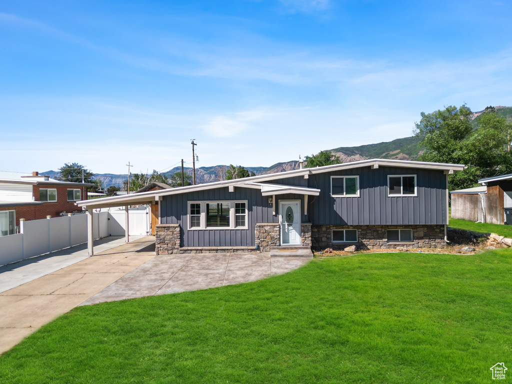 Tri-level home featuring a mountain view, an attached carport, board and batten siding, concrete driveway, and stone siding
