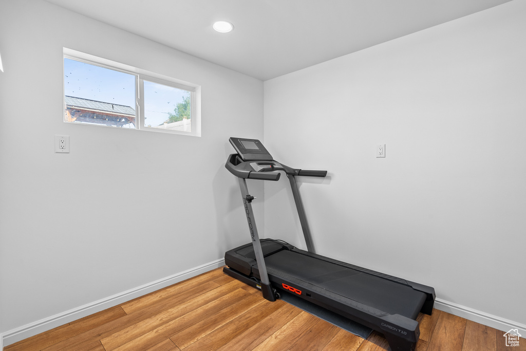 Exercise room with light wood-style flooring and recessed lighting