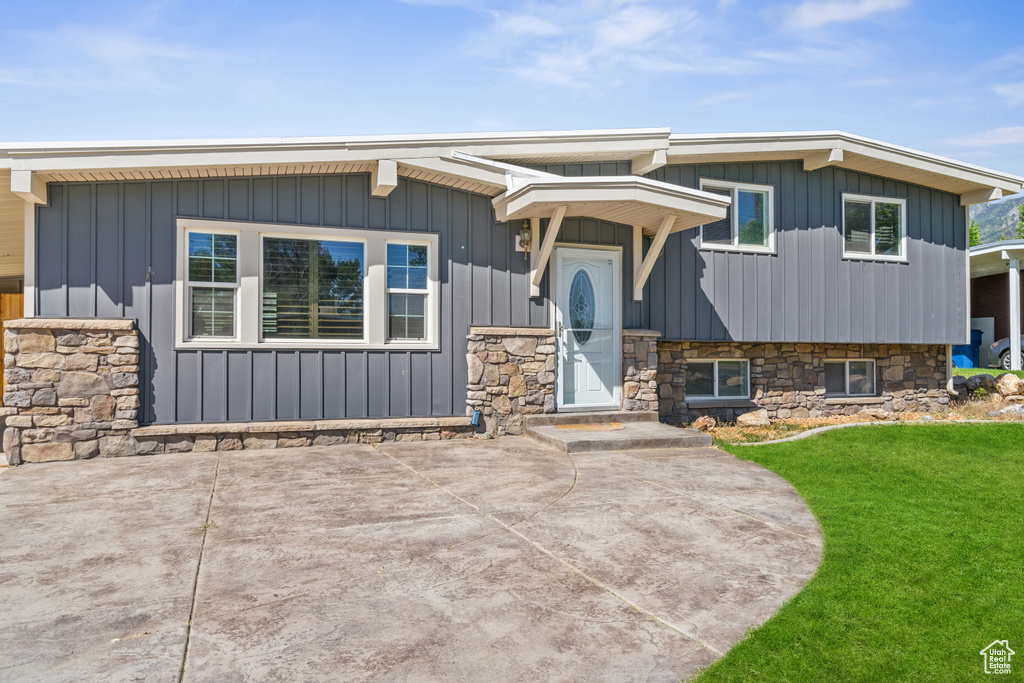 View of front of house with a front yard, board and batten siding, and a patio area