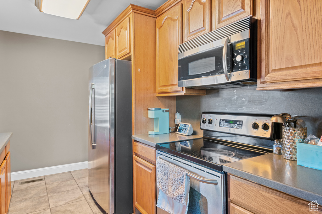 Kitchen with stainless steel appliances, light tile patterned floors, and light brown cabinets