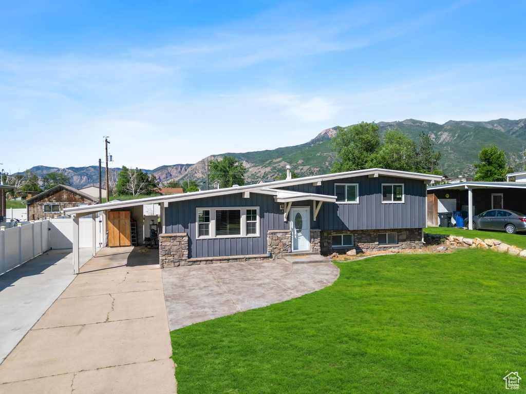 Tri-level home with a mountain view, concrete driveway, stone siding, and board and batten siding