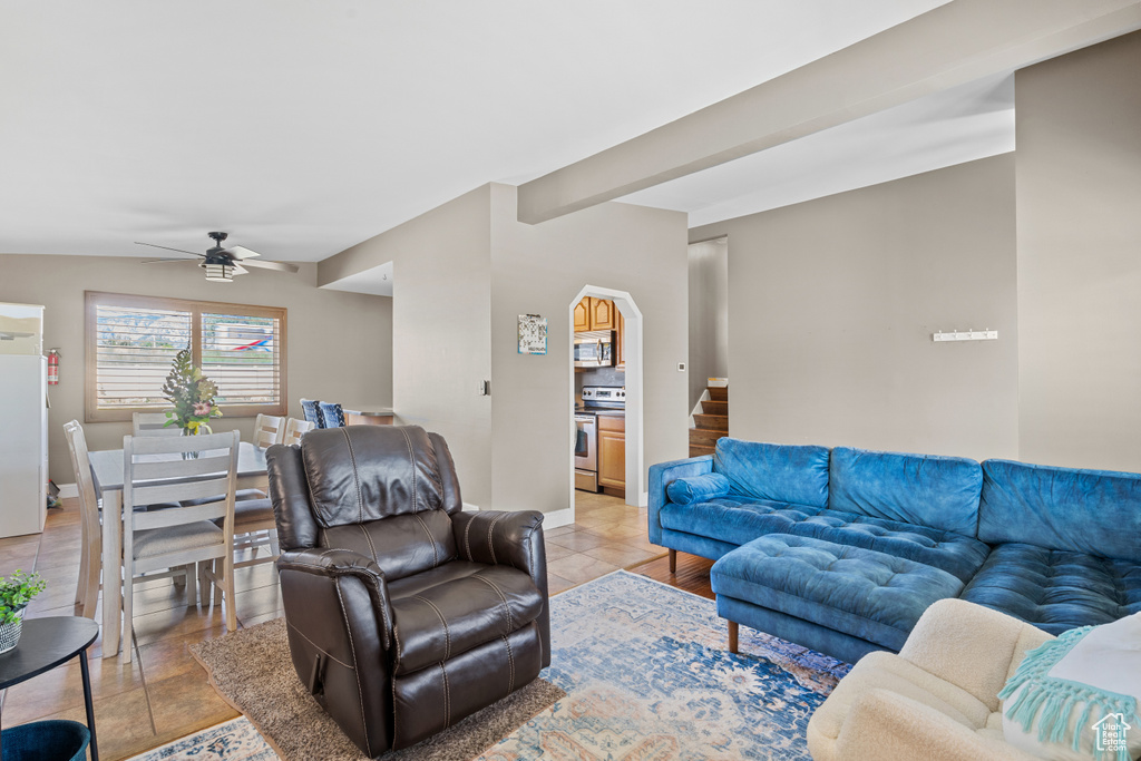 Living area featuring a ceiling fan, light tile patterned flooring, and arched walkways