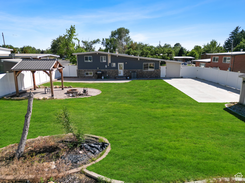 Back of property with a gazebo, an outdoor fire pit, a patio area, and stone siding