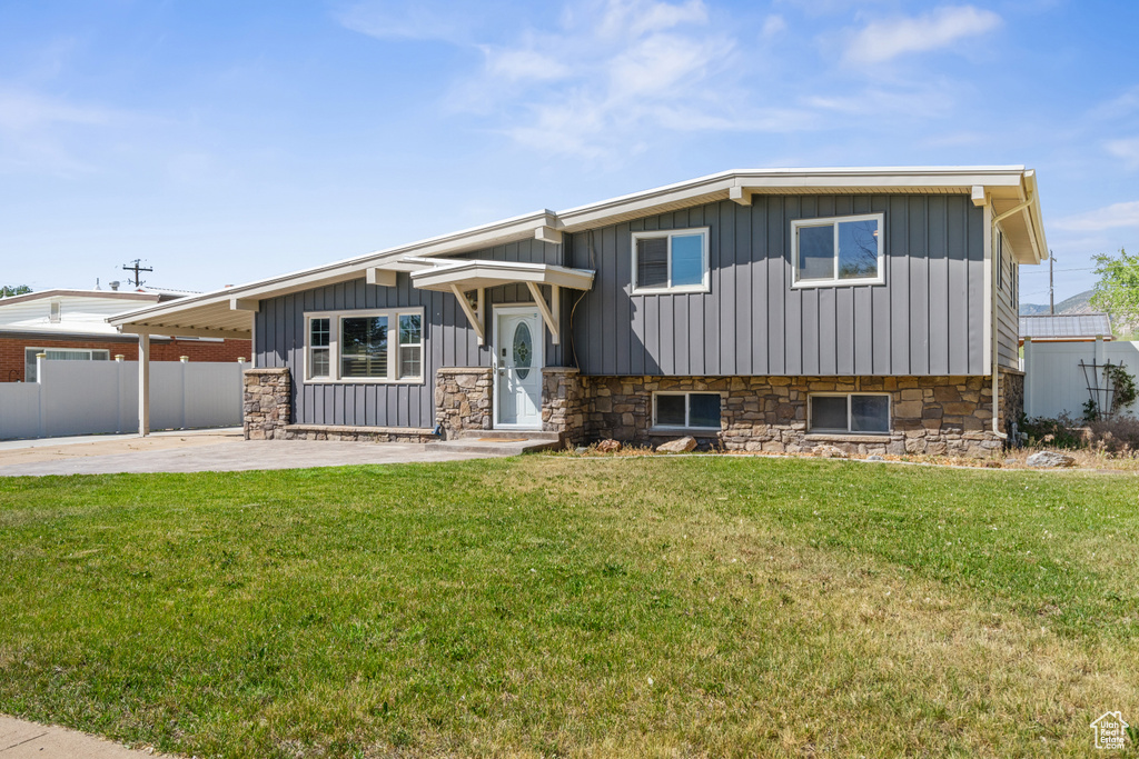 Split level home with board and batten siding, stone siding, and a patio