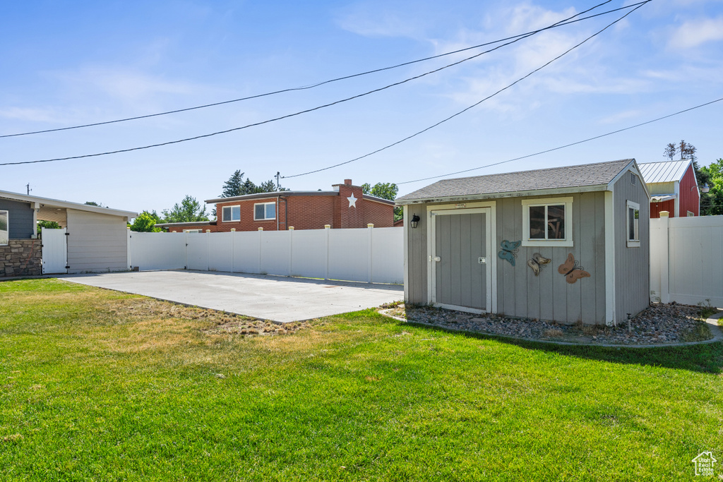 Fenced backyard featuring a patio area and a storage shed