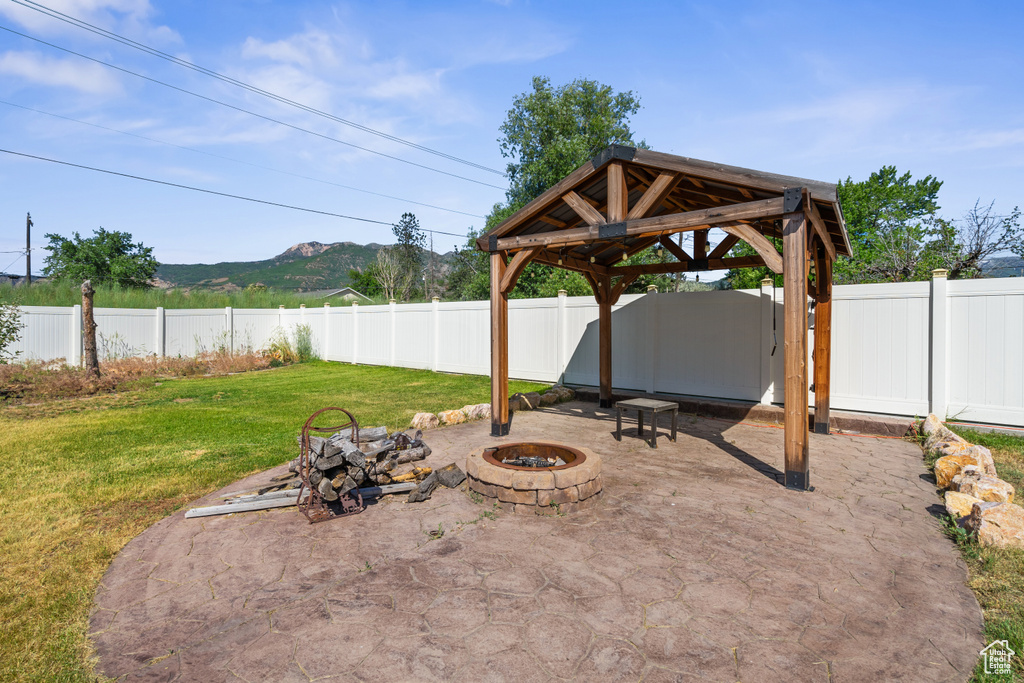 Fenced backyard with a fire pit, a gazebo, a mountain view, and a patio area