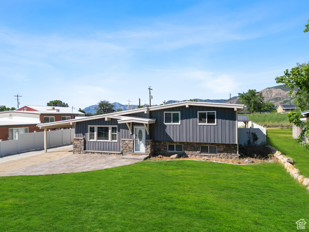 View of front of property with board and batten siding, a mountain view, stone siding, and a carport