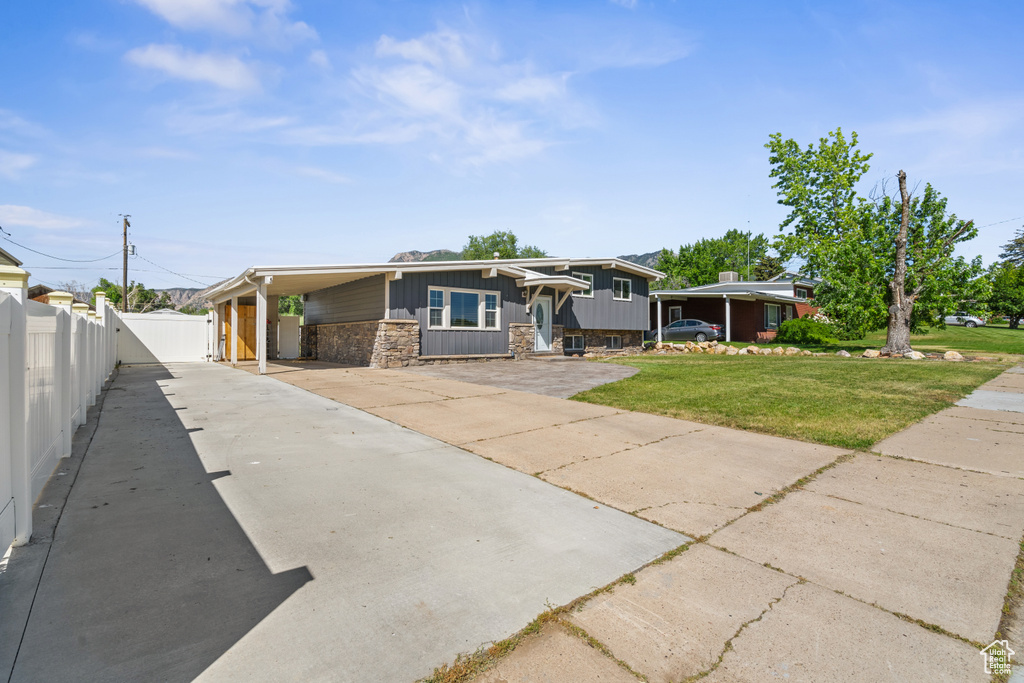View of front of house with concrete driveway, stone siding, and an attached carport