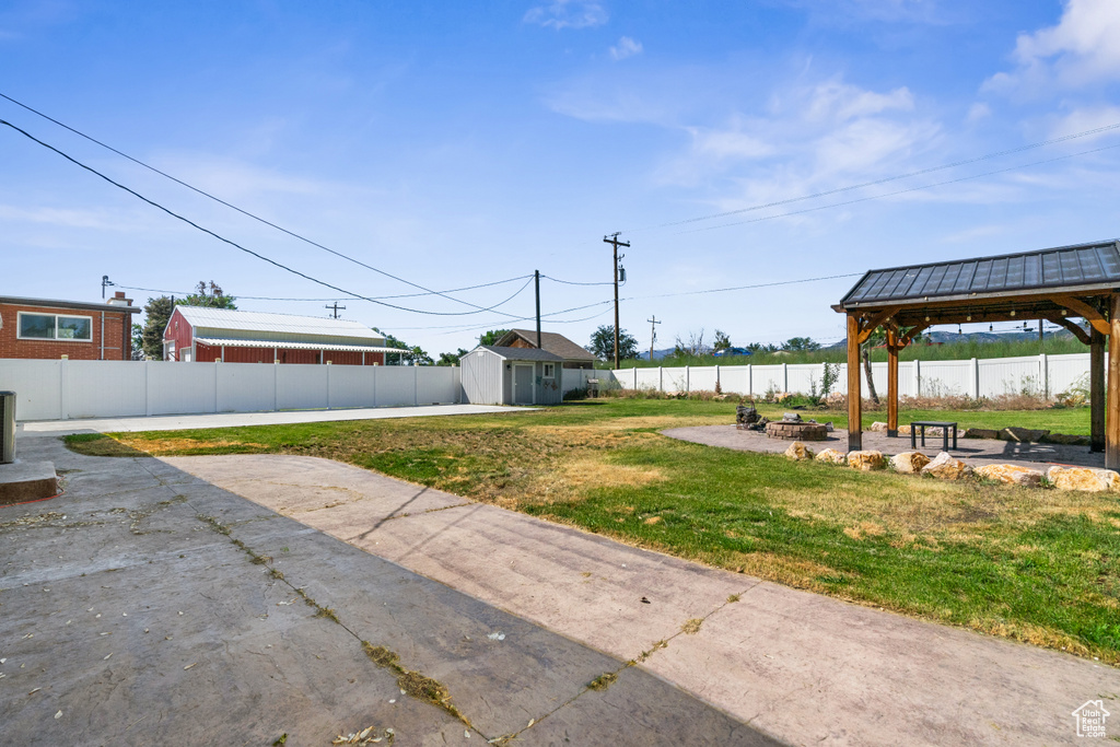 Fenced backyard with a gazebo, a fire pit, a patio area, and a storage shed