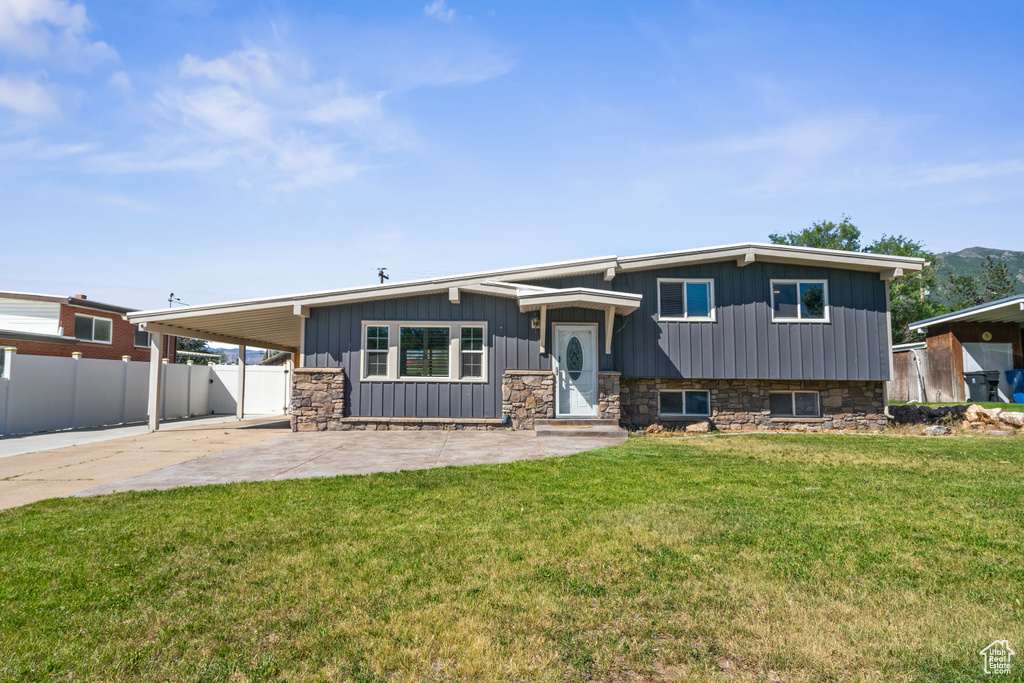 View of front of property featuring a carport, concrete driveway, a patio, stone siding, and board and batten siding